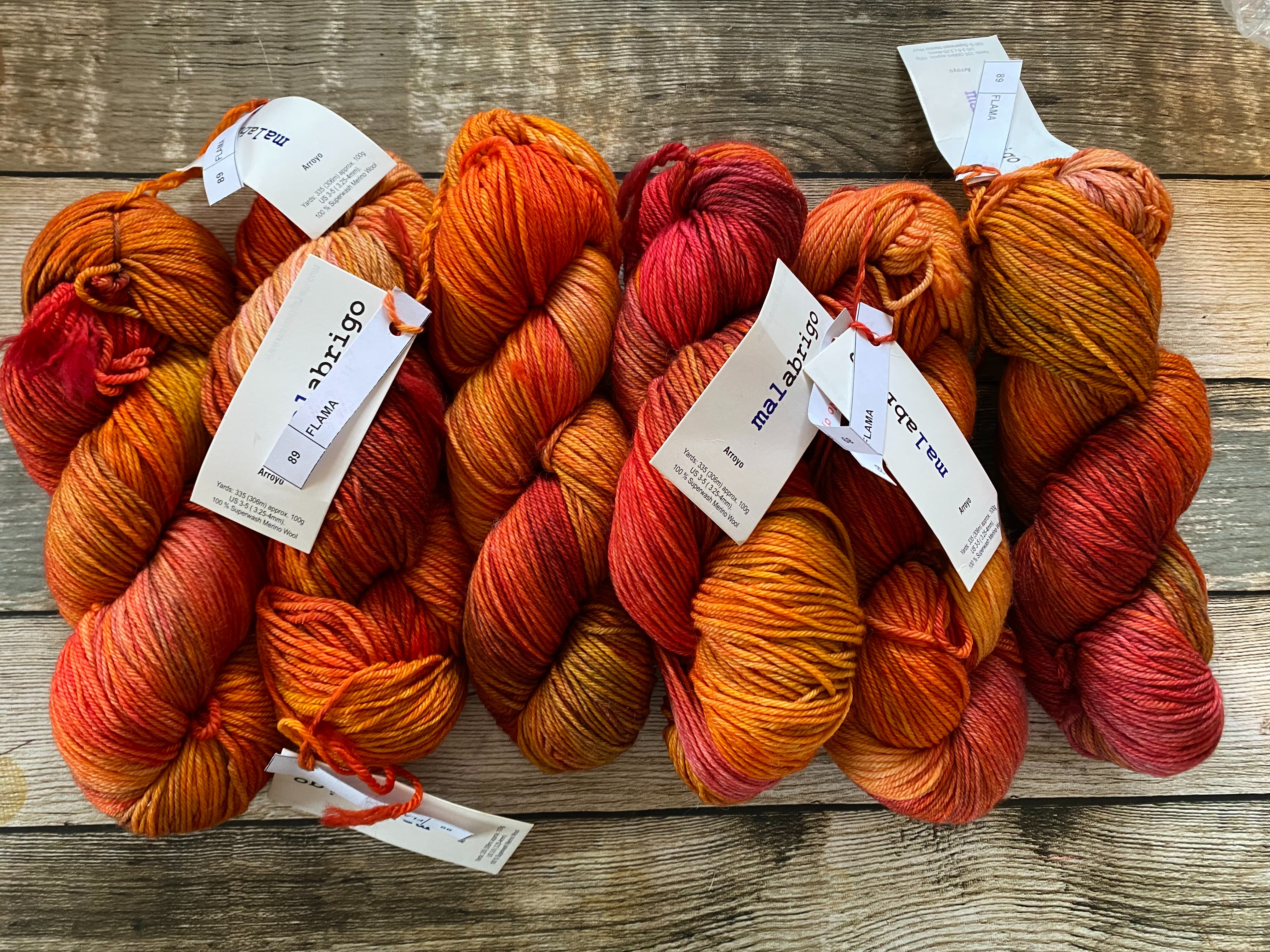 6 skeins of hand-dyed yarn in orange, red, and brown colors