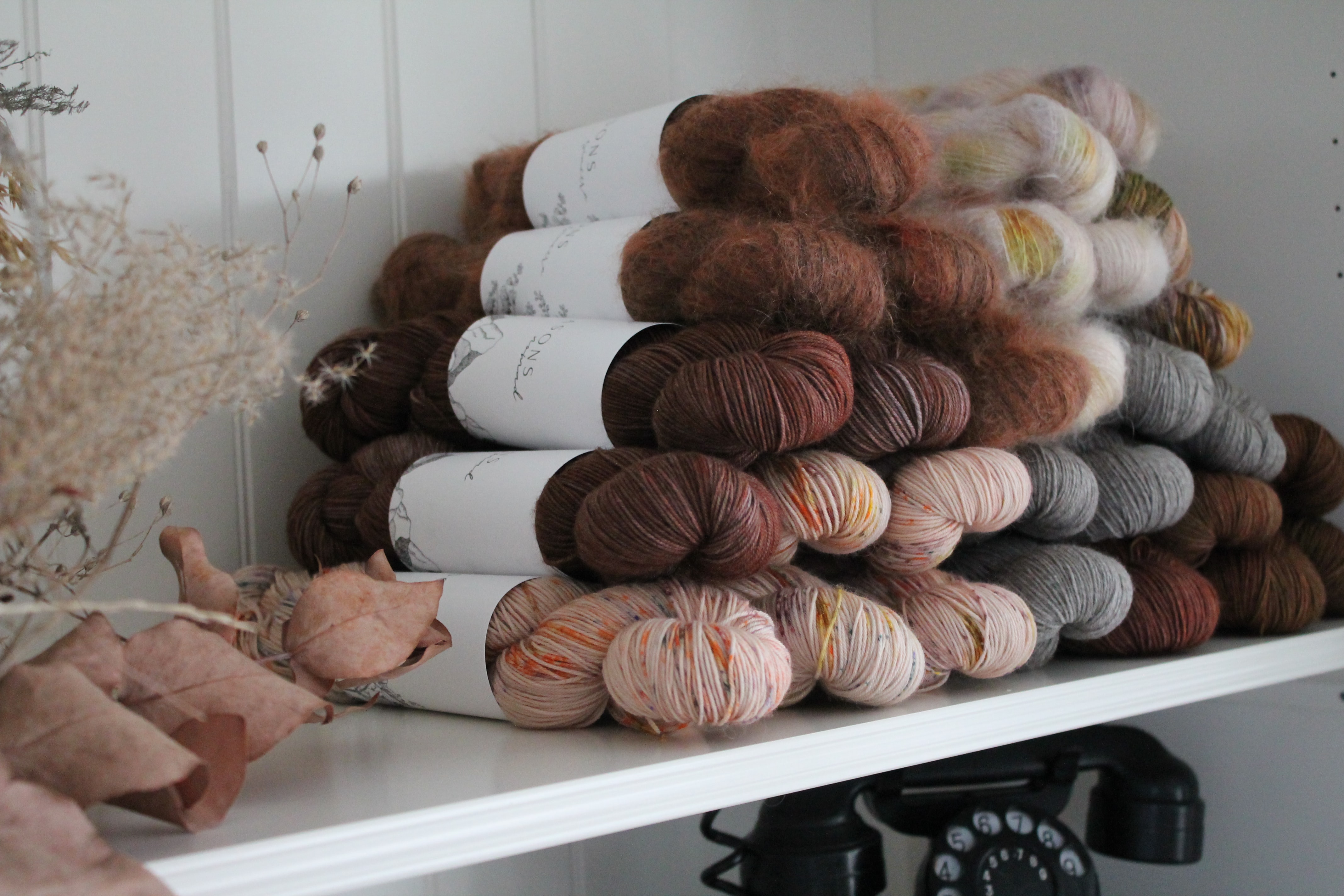 stack of warm-toned yarn sitting on a white shelf